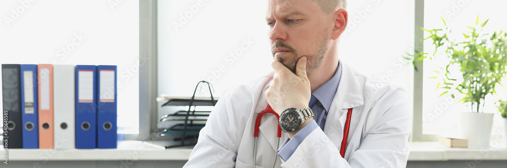 Middle aged medical worker in white uniform confused look in laptop screen Middle aged medical worker in white uniform confused look in laptop screen