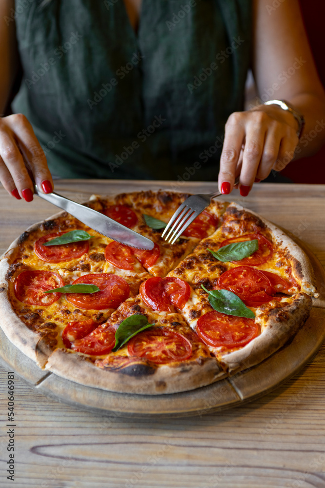 close-up shot of woman eating delicious pizza with cutlery