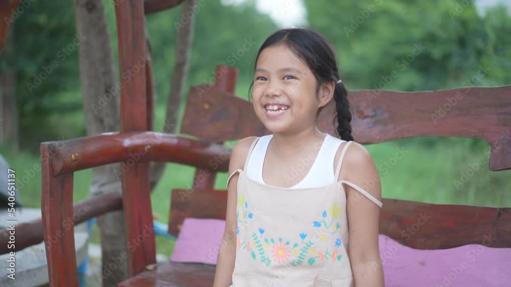 happy asian child or kid girl laughing smiling and happiness sitting relax on wooden swing or wood chair in garden at countryside home on holiday and cheerful enjoyment on green nature outdoor by slow happy asian child or kid girl laughing smiling and happiness sitting relax on wooden swing or wood chair in garden at countryside home on holiday and cheerful enjoyment on green nature outdoor by slow