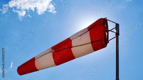 Windsock. Windsock flag. Wind direction indicator. Wind intensity. Windsock in front of blue sky.