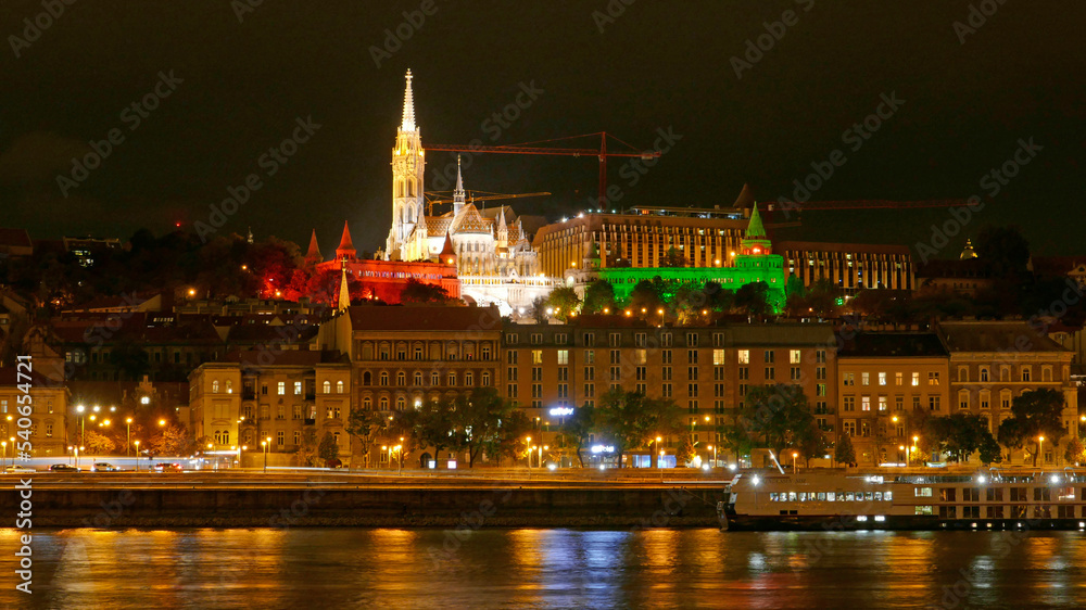 Budapest by night with illuminated Matthias Church and Fisherman's Bastion. On national holidays national flag colors are used: red, white, green.