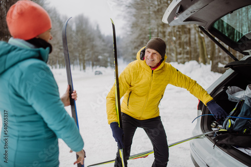 Senior couple near car trunk preparing for winter skiing.