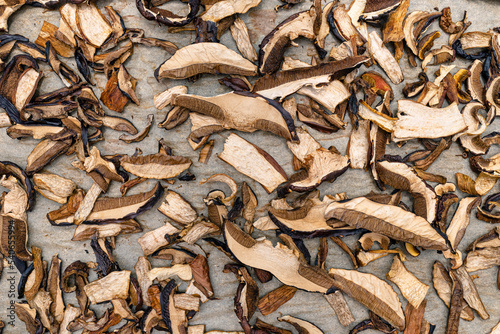 Background of sliced and dried edible mushrooms, lying on baking paper, top view.