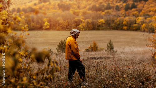 a man in a yellow jacket walks through the autumn forest
