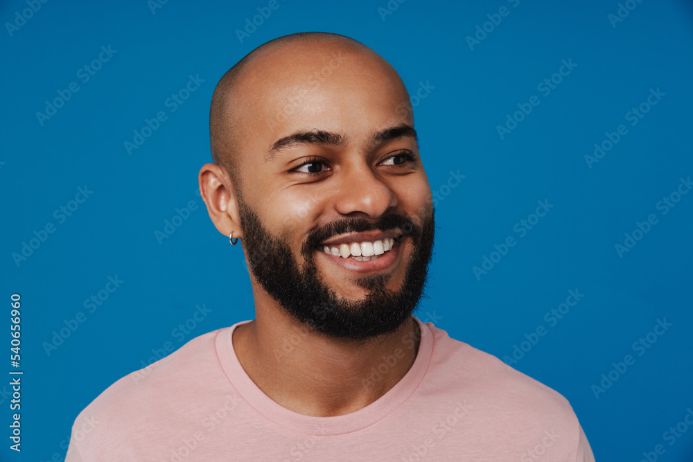 Black bald man with beard smiling and looking aside Black bald man with beard smiling and looking aside