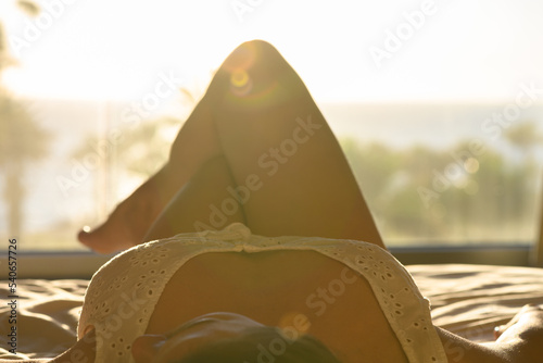 Canvastavla Beautiful woman in nightgown lying on the bed against sea and palm trees at summ