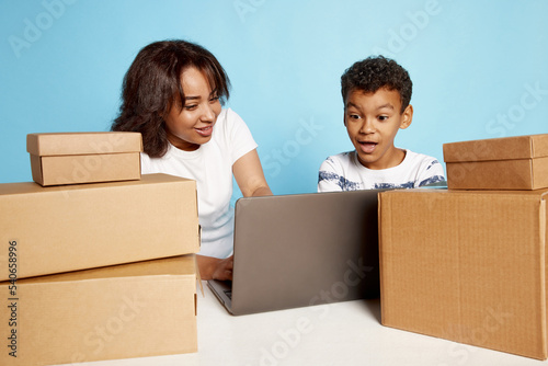 Portrait of excited woman and teen boy doing online order on laptop over blue background. Fast shopping