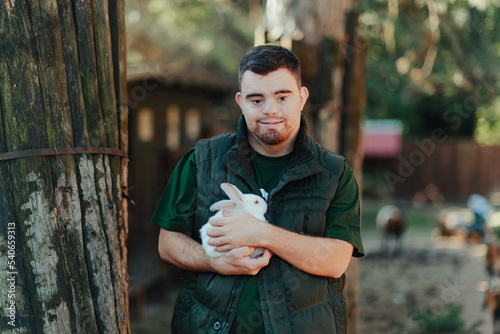 Fényképezés Caretaker with down syndrome taking care of animals in zoo, stroking rabbit