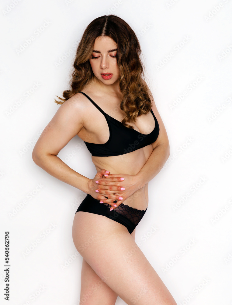 Fototapeta premium Woman of 30-35 years old in black casual underwear posing on white background in studio. Natural normal woman body. Advertising underwear. Different angle view of a face.