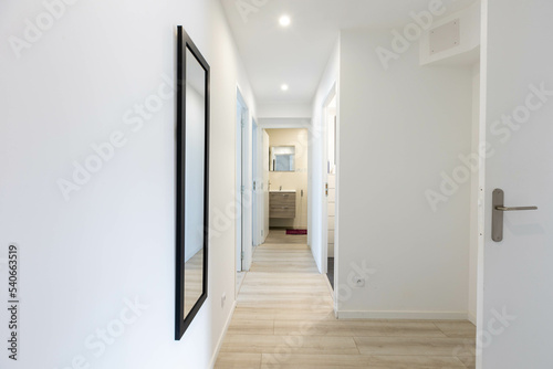 long couloir d'un appartement neuf au mur blanc avec plusieurs portes