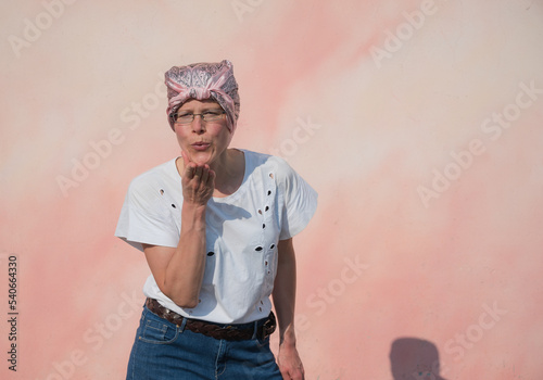 Woman with pink bandana blows a kiss on camera. Close up.