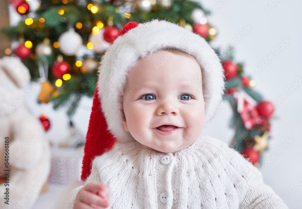 Santa baby. Christmas tree background. Happy New Year! Child in Santa's hat. Santa baby. Christmas tree background. Happy New Year! Child in Santa's hat.
