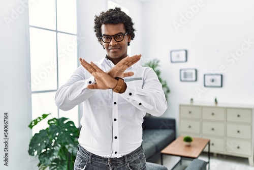 African psychologist man at consultation office rejection expression crossing arms and palms doing negative sign, angry face