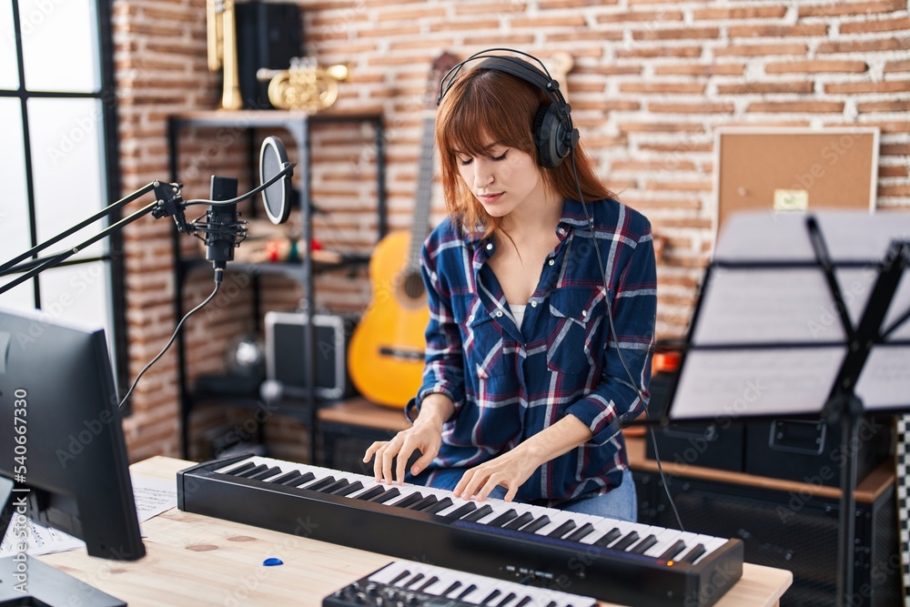 Young woman musician playing piano keyboard at music studio - obrazy, fototapety, plakaty 