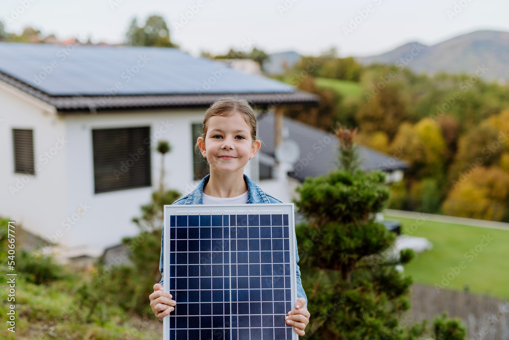 Little girl holding photovoltaics solar panel. Alternative energy, saving resources and sustainable lifestyle concept.