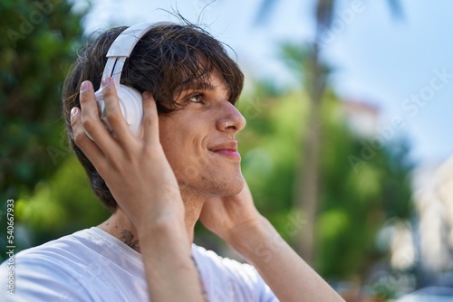 Young blond man smiling confident listening to music at park © Krakenimages.com