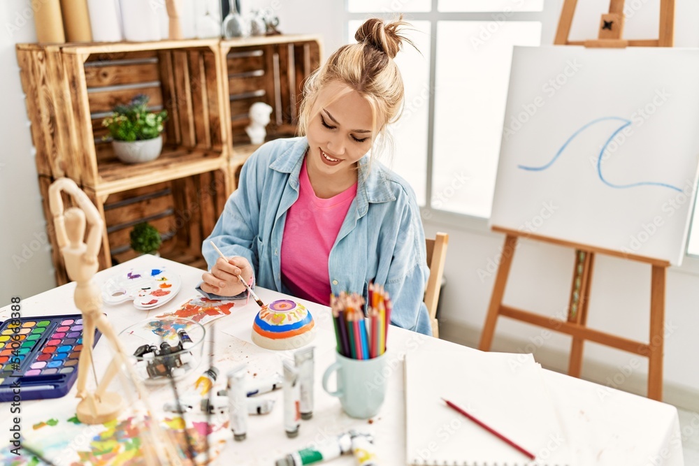 Young caucasian woman artist smiling confident drawing ceramic at art studio