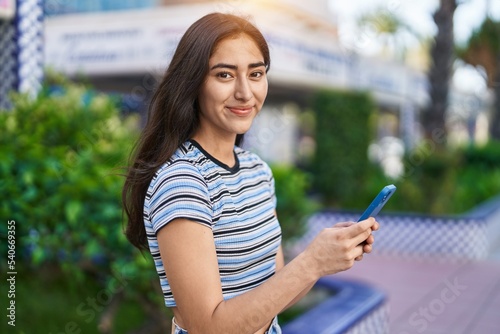 Young hispanic girl smiling confident using smartphone at park