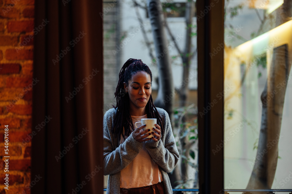 Young adult woman drinks coffee at home