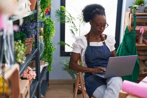 African american woman florist using laptop at florist store