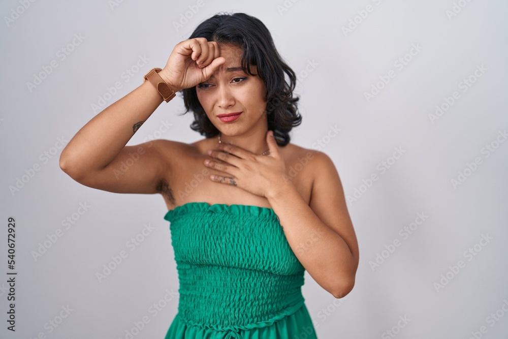 Young hispanic woman standing over isolated background touching forehead for illness and fever, flu and cold, virus sick Young hispanic woman standing over isolated background touching forehead for illness and fever, flu and cold, virus sick