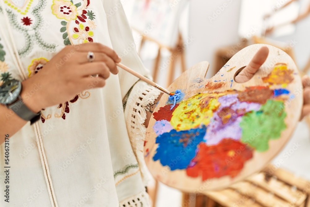 Young hispanic woman mixing color on palette at art studio Young hispanic woman mixing color on palette at art studio