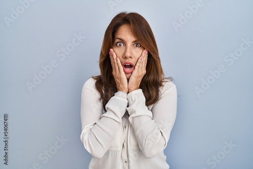 Hispanic woman standing over isolated background afraid and shocked, surprise and amazed expression with hands on face