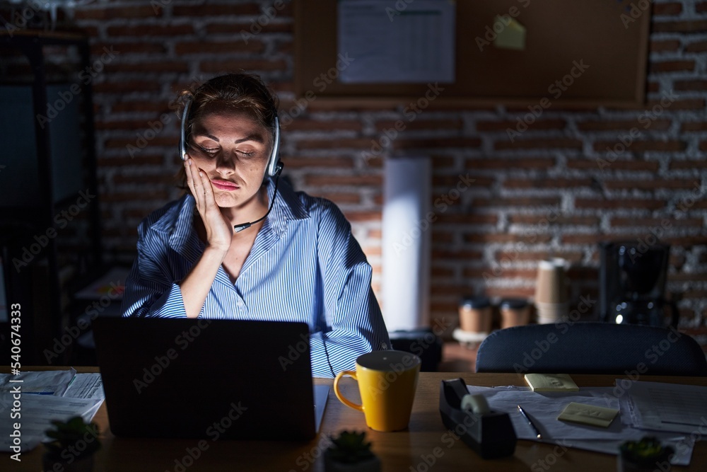Beautiful brunette woman working at the office at night thinking looking tired and bored with depression problems with crossed arms.