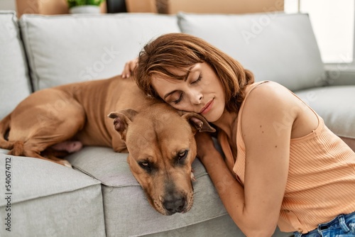 Young caucasian woman sleeping sitting on floor with dog at home