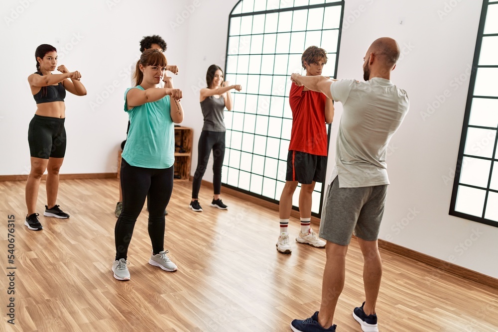 Group of young people boxing with personal trainer at sport center.