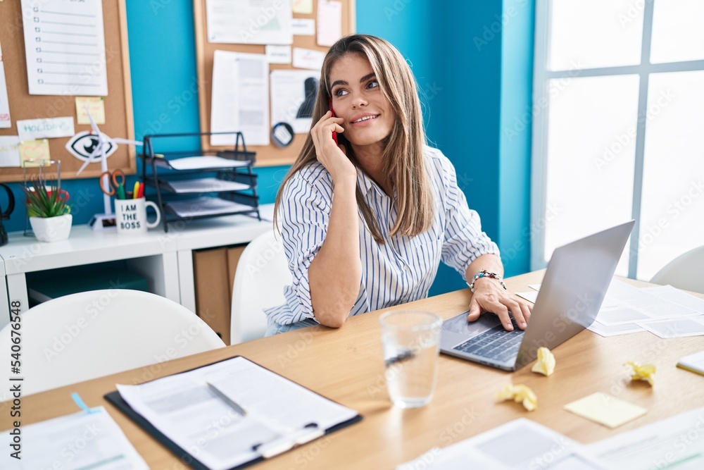 Obraz premium Young beautiful hispanic woman business worker using laptop talking on smartphone at office