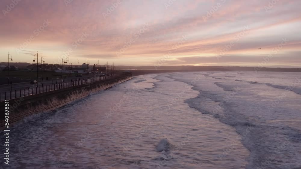 Waves reflect off seawall on Tramore Strand seaside at dawn sunrise Waves reflect off seawall on Tramore Strand seaside at dawn sunrise