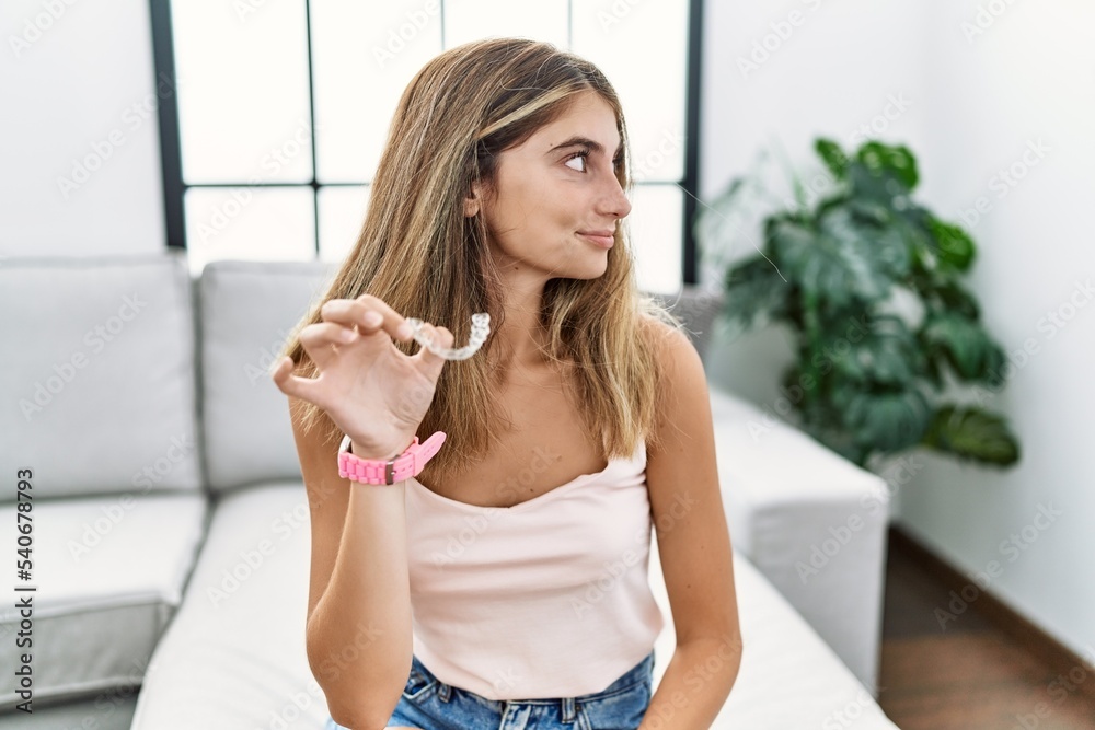 Young blonde woman holding invisible aligner orthodontic looking to side, relax profile pose with natural face and confident smile. Young blonde woman holding invisible aligner orthodontic looking to side, relax profile pose with natural face and confident smile.