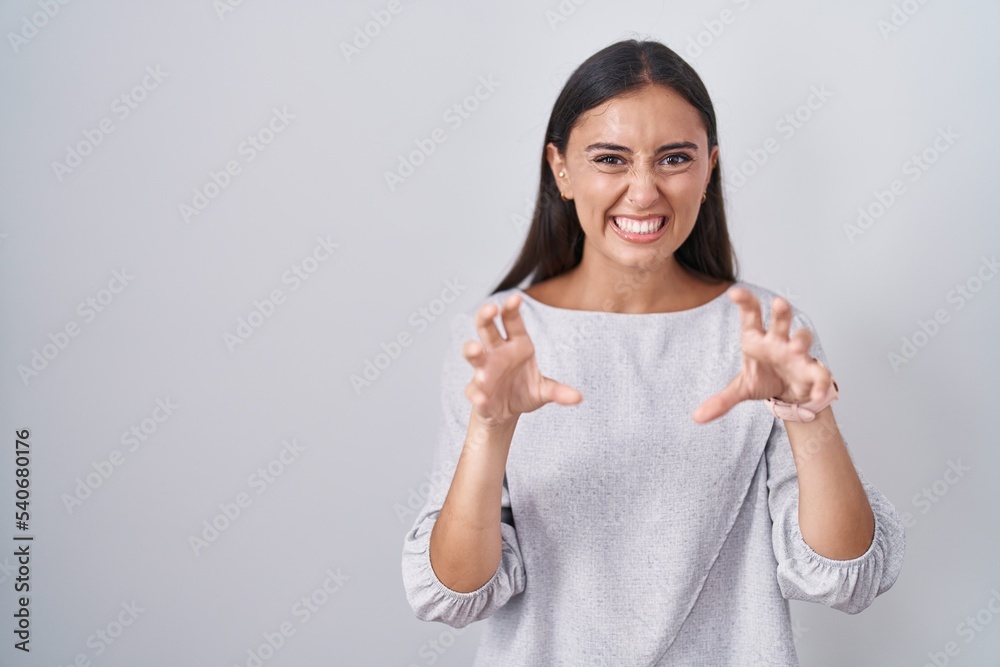 Young hispanic woman standing over white background smiling funny doing claw gesture as cat, aggressive and sexy expression Young hispanic woman standing over white background smiling funny doing claw gesture as cat, aggressive and sexy expression
