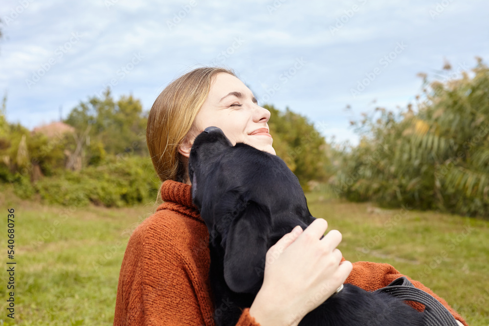a happy woman hugs her black labrador dog while walking in an autumn park a happy woman hugs her black labrador dog while walking in an autumn park