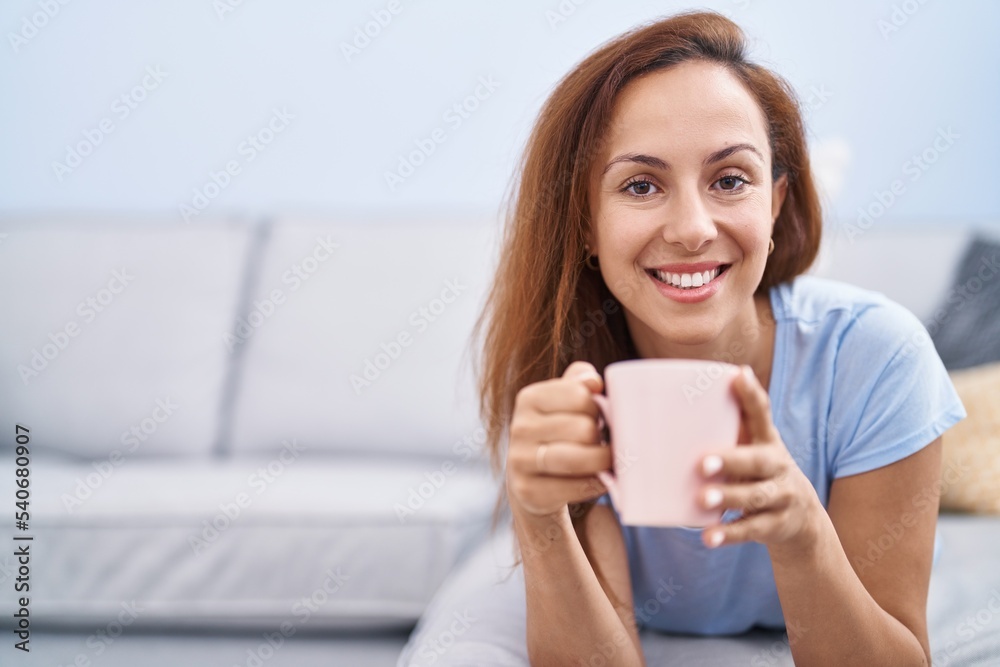 Young woman drinking coffee lying on sofa at home Young woman drinking coffee lying on sofa at home