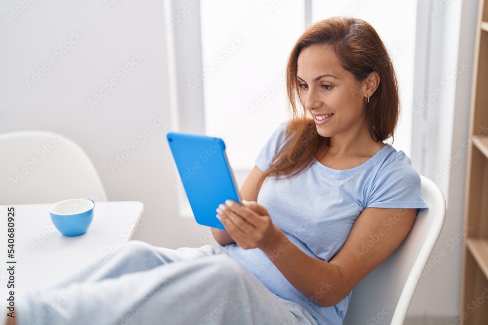 Young woman using touchpad and drinking coffee at home Young woman using touchpad and drinking coffee at home