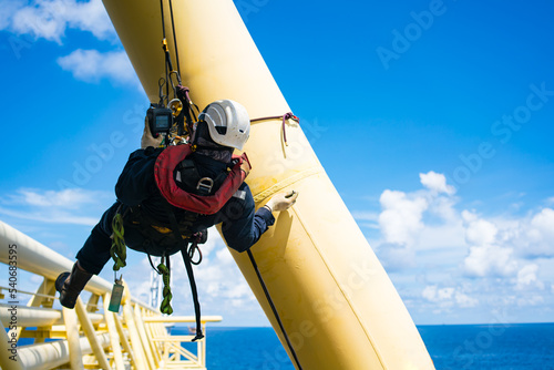 Pipe inspectors in the petrochemical industry by rappelling for inspection and using ultrasonic instruments. photo