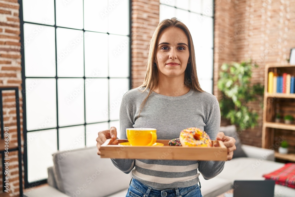 Young woman holding tray with breakfast food skeptic and nervous, frowning upset because of problem. negative person.