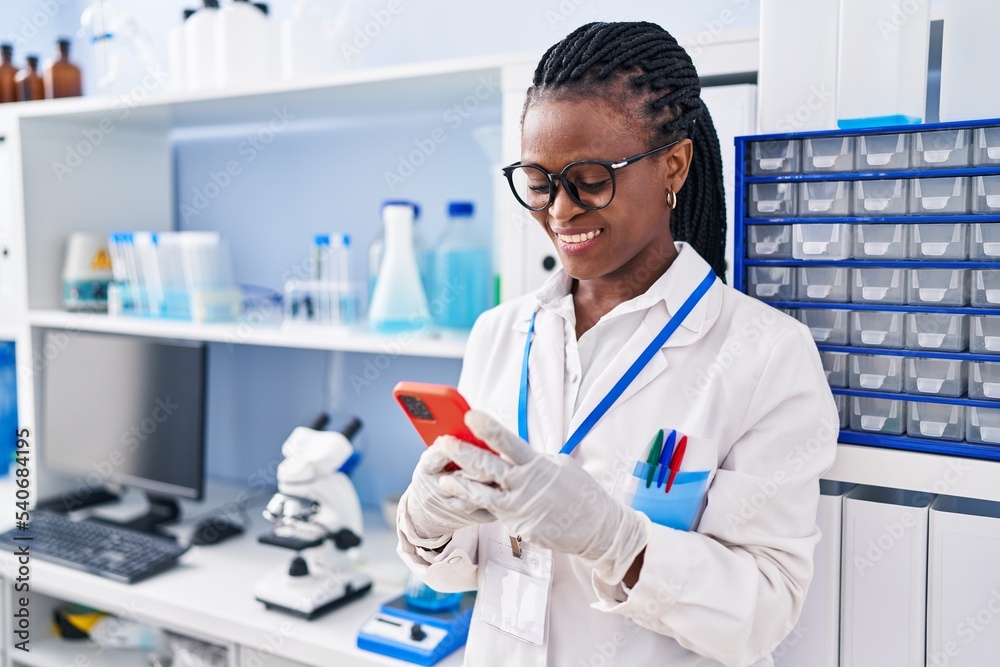 African american woman scientist smiling confident using smartphone at laboratory