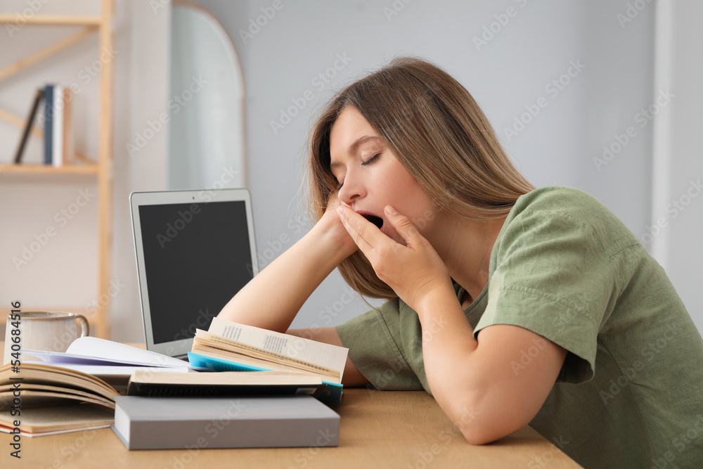 Sleepy young woman studying at wooden table indoors Sleepy young woman studying at wooden table indoors