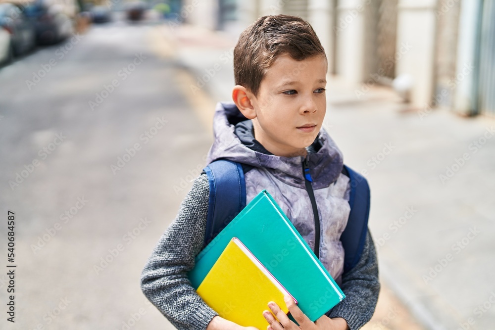 Blond child student holding books standing at street Blond child student holding books standing at street