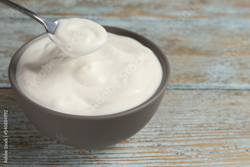 Ceramic bowl with delicious organic yogurt on wooden table, closeup