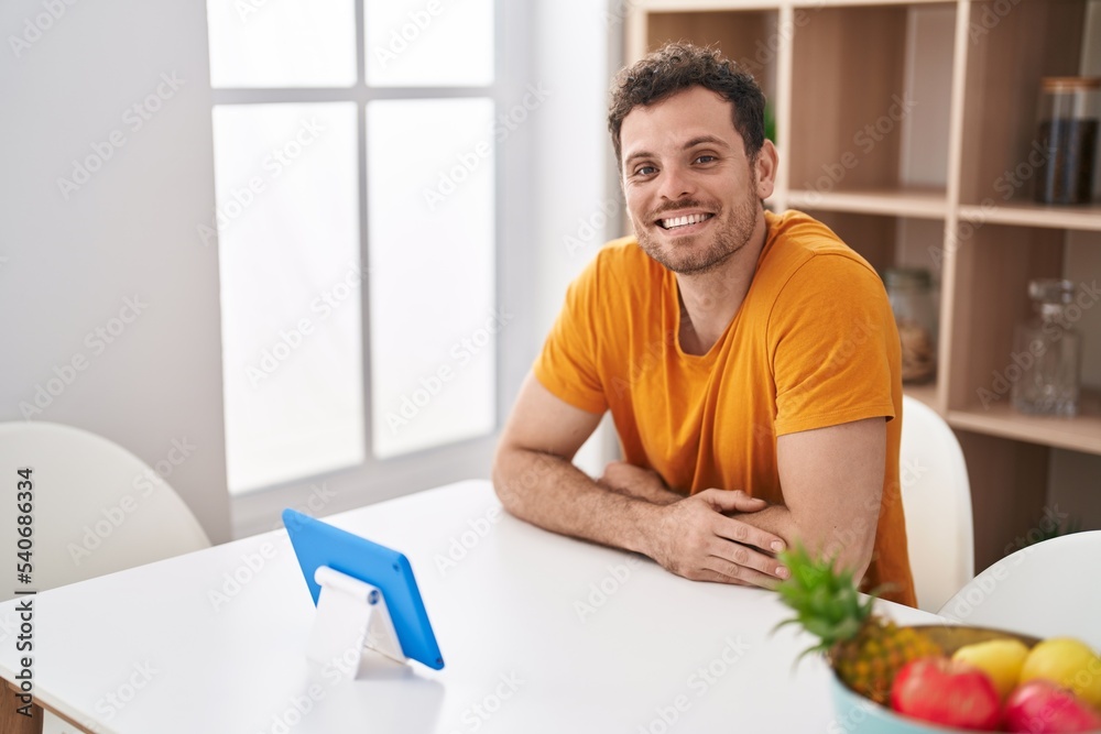 Young hispanic man watching video on touchpad at home Young hispanic man watching video on touchpad at home
