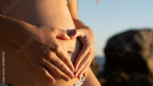 pregnant belly in the first trimester of pregnancy. Close up picture of a pregnant woman holding her belly in the first trimester, otudoor