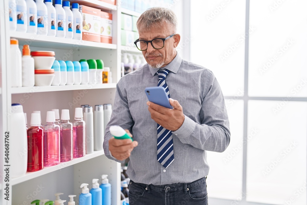 Middle age grey-haired man customer make photo by smartphone to medicine bottle at laboratory Middle age grey-haired man customer make photo by smartphone to medicine bottle at laboratory