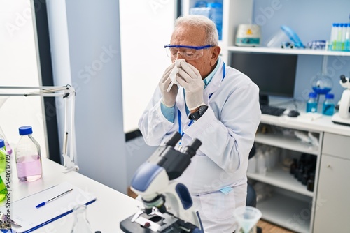 Senior man wearing scientist uniform using napkin at laboratory