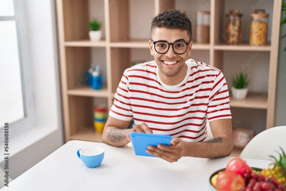 African american man using touchpad drinking coffee at home African american man using touchpad drinking coffee at home