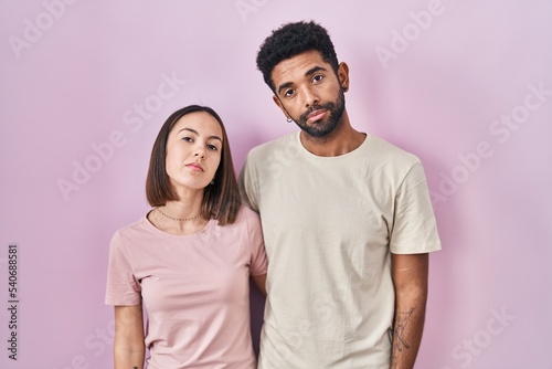 Young hispanic couple together over pink background looking sleepy and tired, exhausted for fatigue and hangover, lazy eyes in the morning.