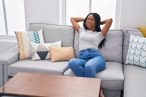 African american woman relaxed with hands on head sitting on sofa at home